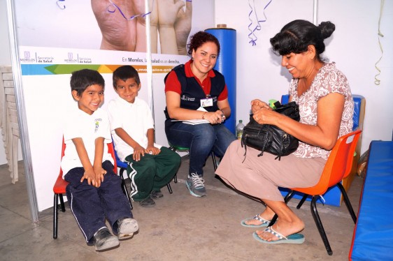 Servidora pública llenando formulario con dos niños y su madre 